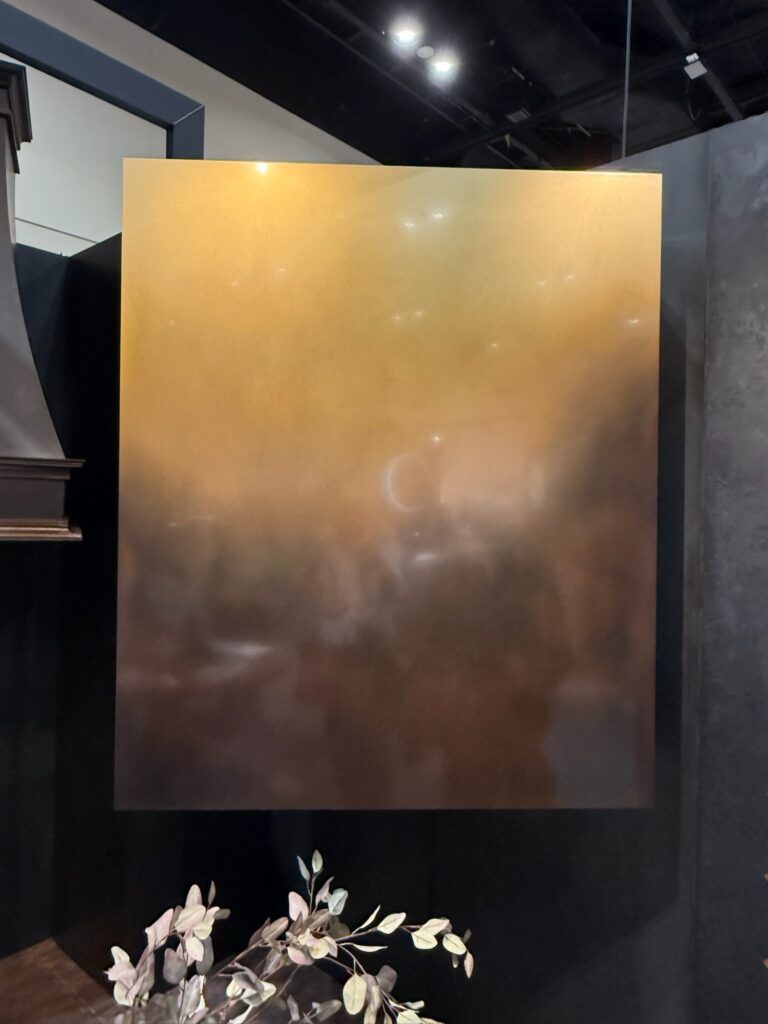 Image shows a custom patinated ombre metal range hood in rectangular shape.  The top portion of the hood is brass and as your work your way down the range hood the metal turns darker more bronze. 