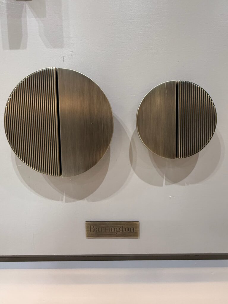 Cabinet or cupboard pull in circular shape features one half that is smooth and one that has a striking ribbed texture.  The finish is dark brushed brass.