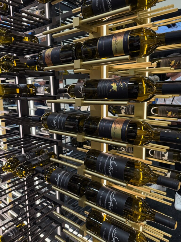 Brass metal wine rack designed for a wall.  Wine bottles are hung horizontally. 