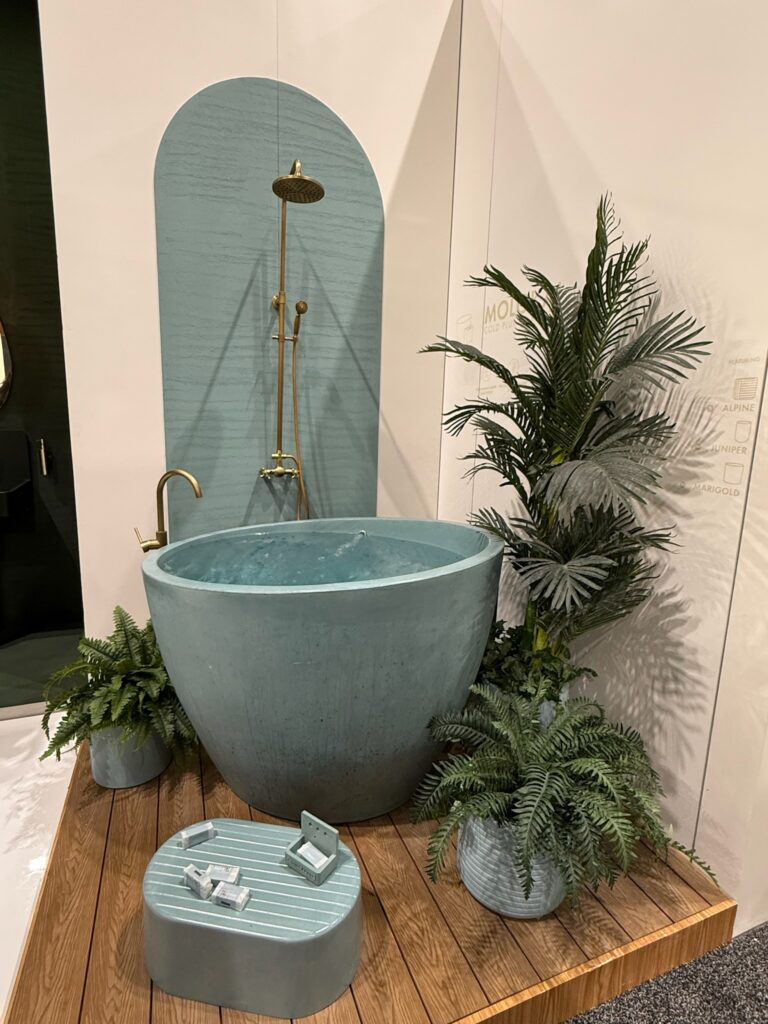 Freestanding round Bathtub in the color turquoise. It is designed for sitting rather than laying down. Has a built in seat. also has a brass faucet and brass shower head. Can be used as a cold plunge. 