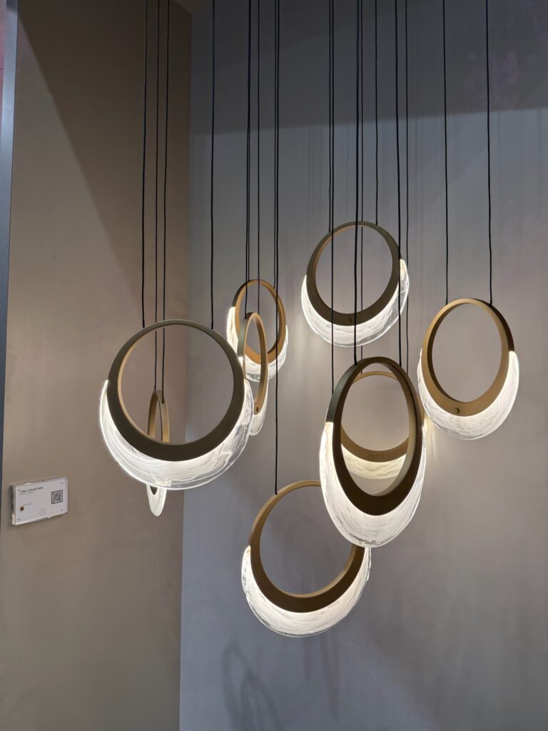 Sculptural light fixture with crescent shaped clear and white glass set inside golden rings. Individual pendant lights are suspended by slender black cables creating a floating celesital effect. 